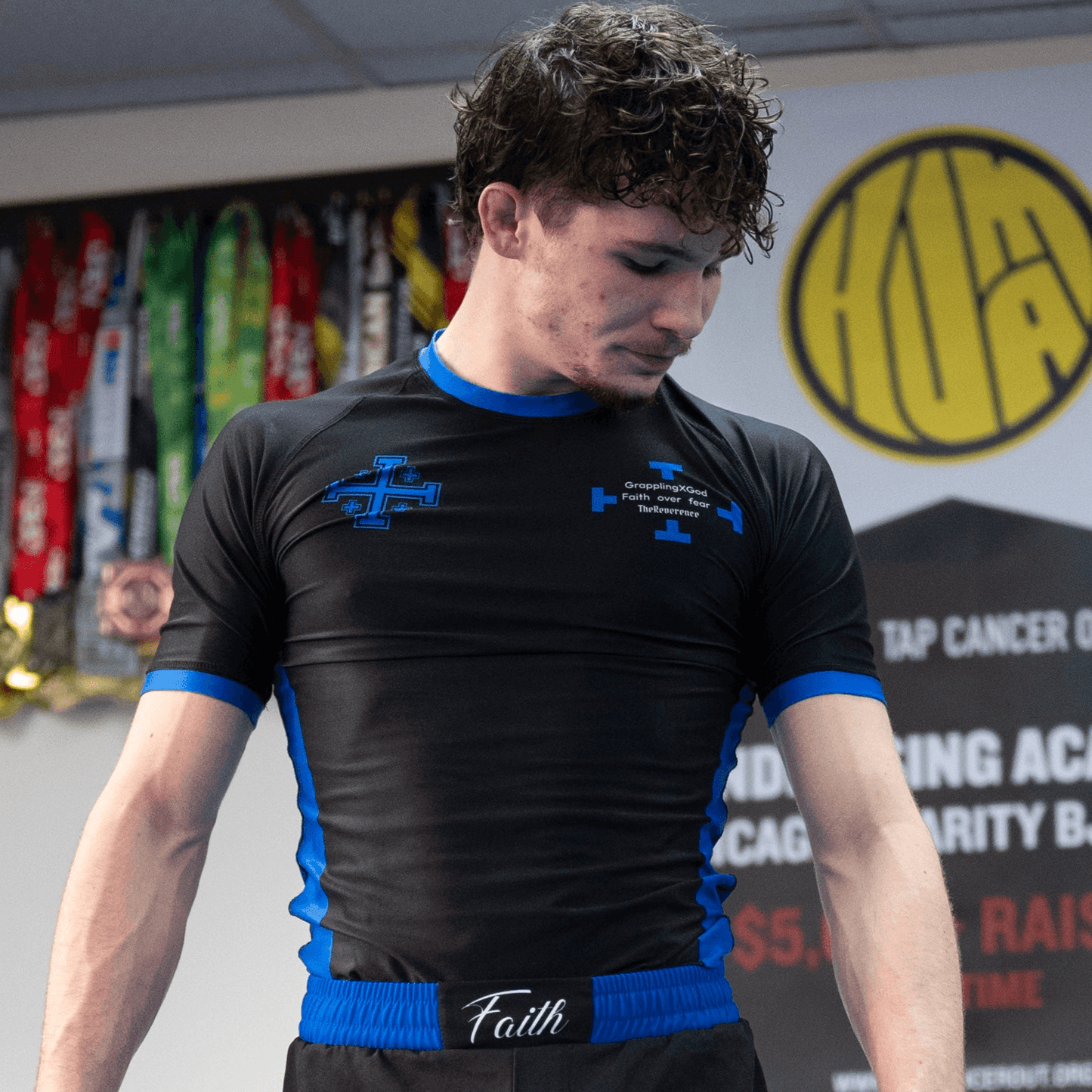 Person wearing a black and blue athletic shirt with visible branding in a gym setting