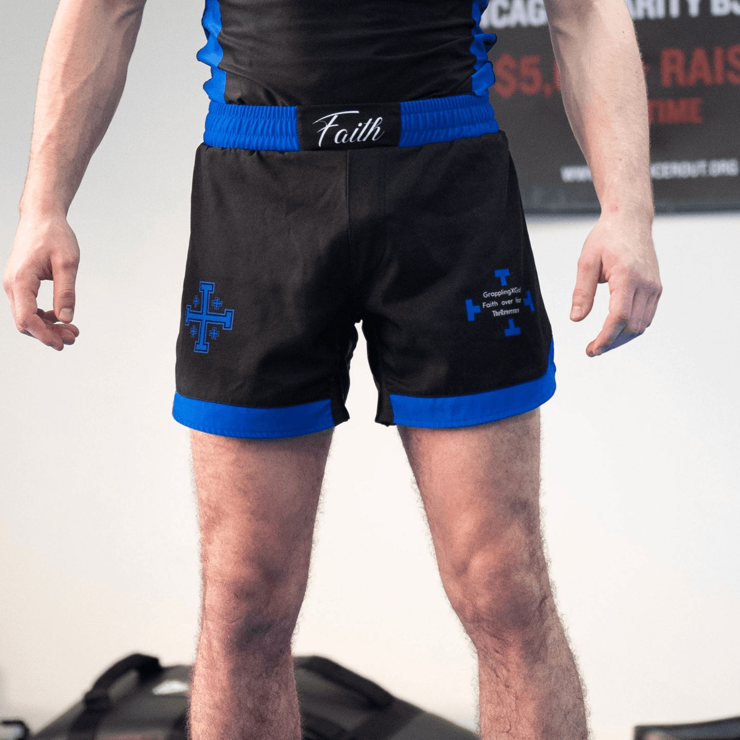 Black shorts with blue accents worn by a person, featuring the brand 'Faith'.