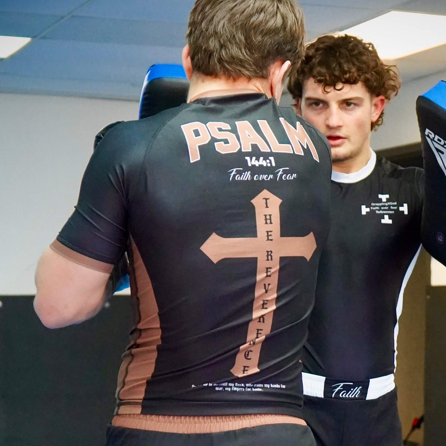 Two individuals wearing athletic shirts with text and designs, one featuring 'PSALM 147:1 Faith over Fear'.