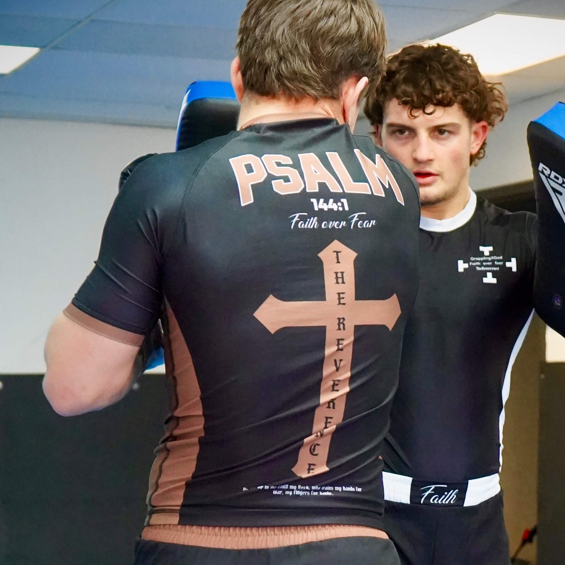 Two individuals wearing athletic shirts with text and designs, one featuring 'PSALM 147:1 Faith over Fear'.