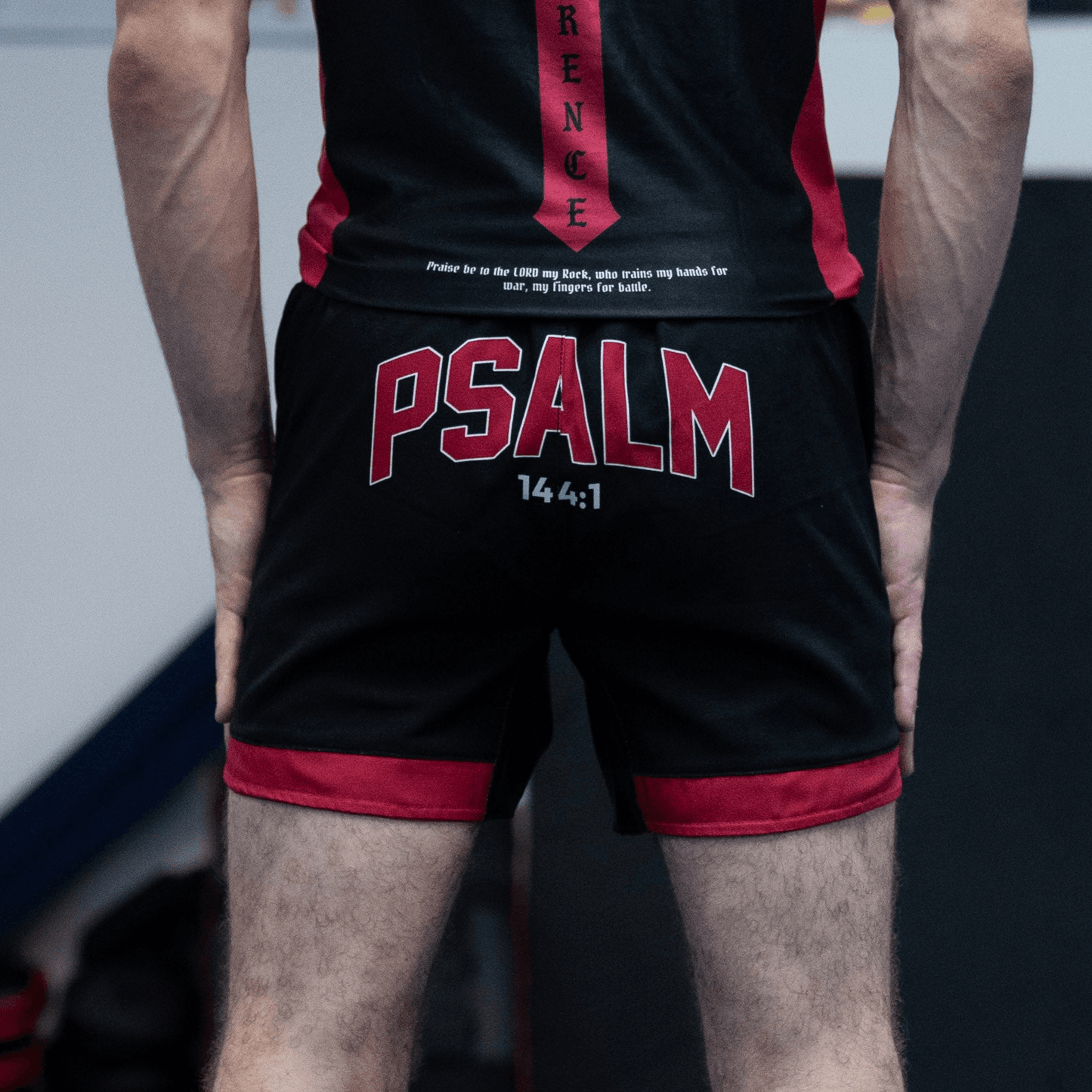 Man wearing black and red shorts with "PSALM" writing on the back 