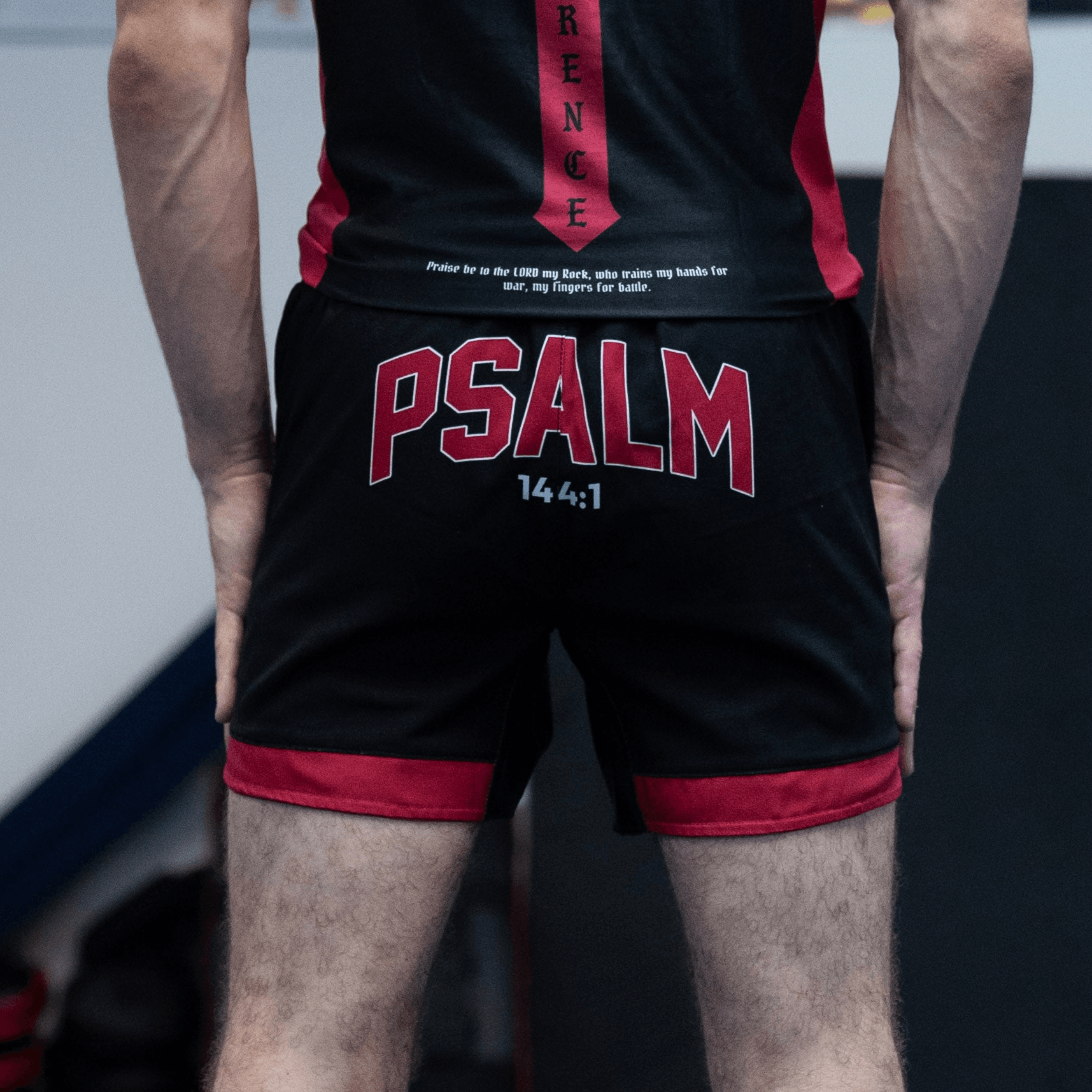 Man wearing black and red shorts with "PSALM" writing on the back 