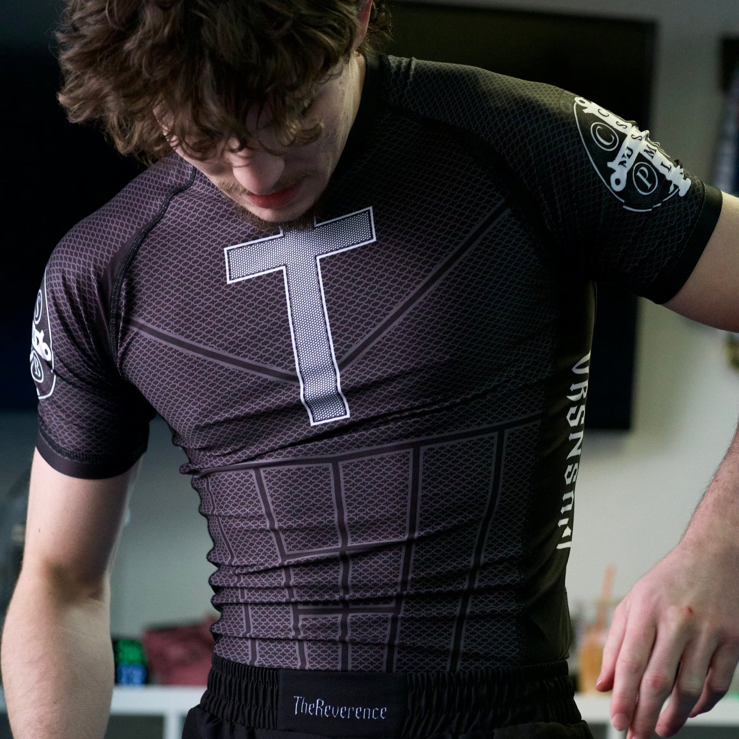 Person wearing a black athletic outfit with a logo, standing indoors.