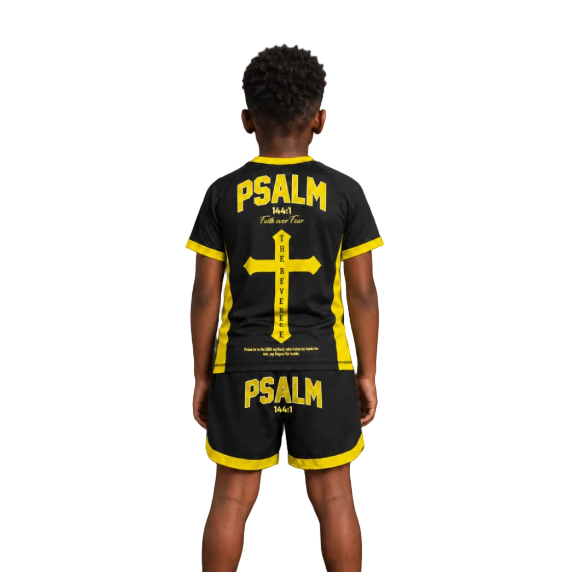 A child shown from the back wearing a black short-sleeve shirt and matching shorts with bright yellow trim and large yellow 'PSALM 1501' and cross graphics on the back. The image has 'The Reverence' branding, 'YELLOW COLORWAY' text, and a large 'BACK' label on a dark studio background.