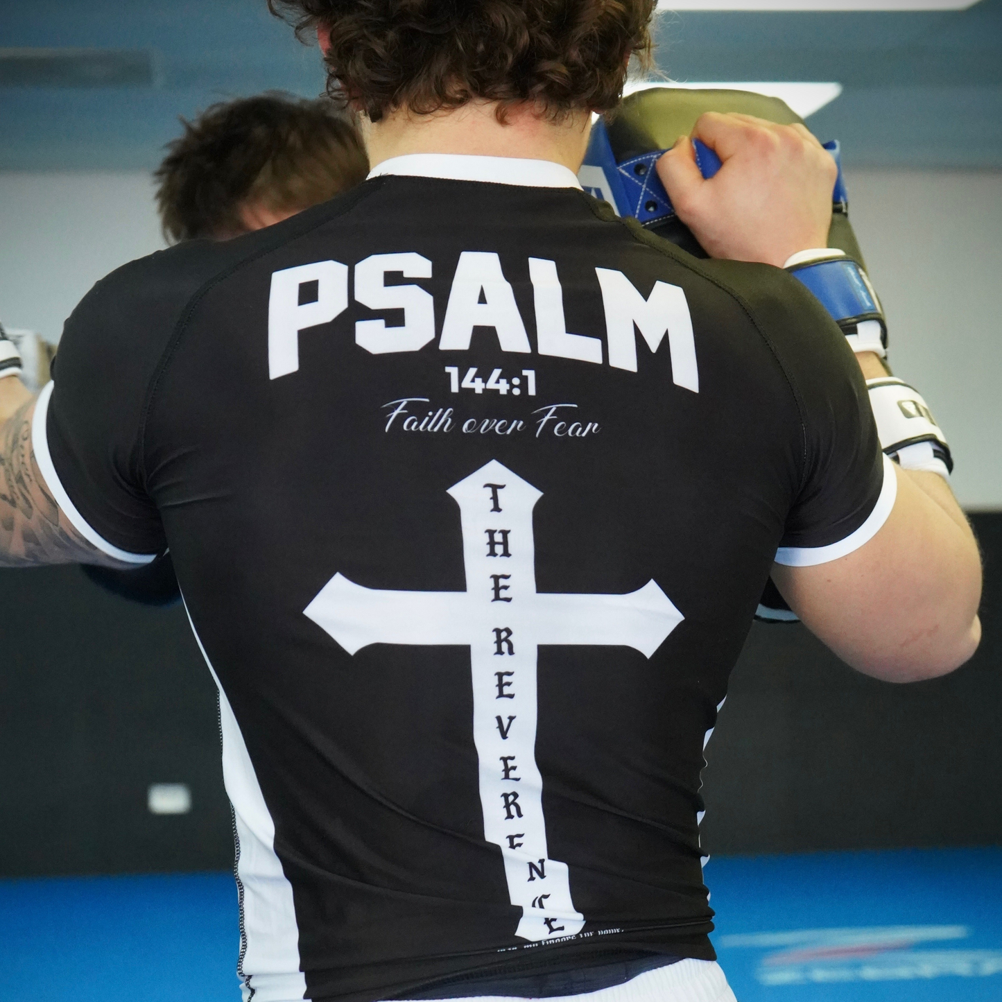 Person wearing a black t-shirt with 'PSALM 144:1 Faith over Fear' text and cross design.