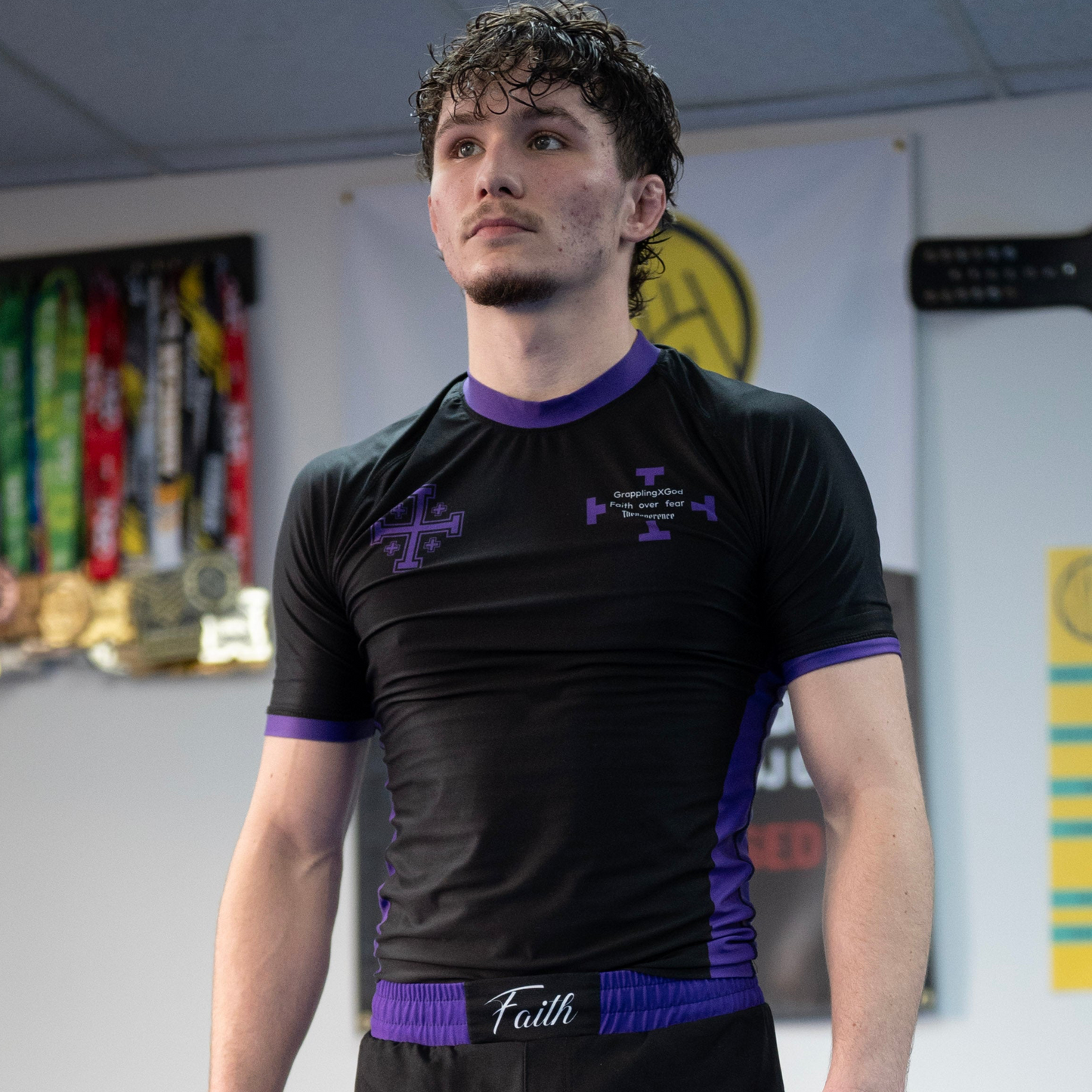 Person wearing a black and purple sports jersey in an indoor setting with trophies in the background
