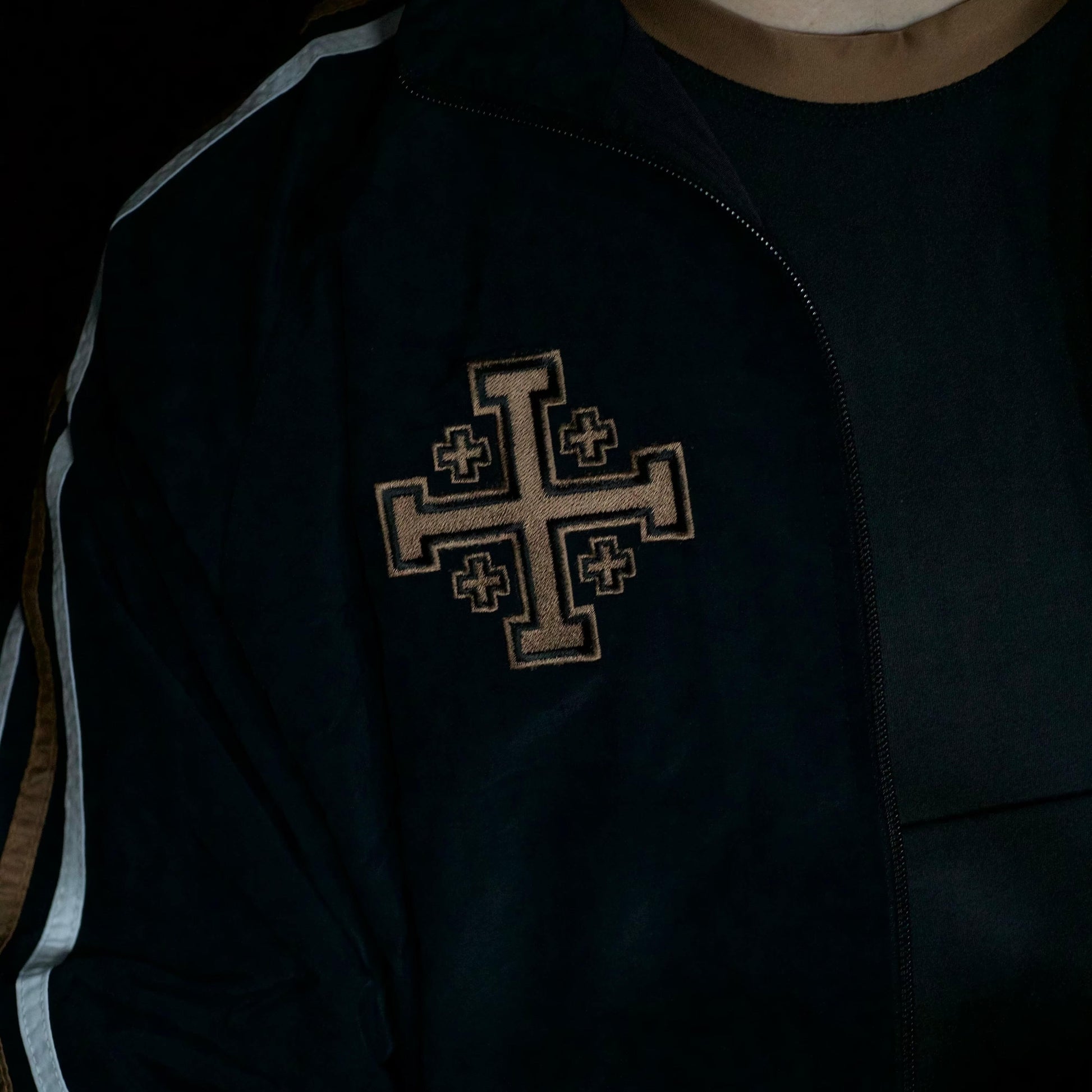 Black jacket with a central cross emblem on a dark background