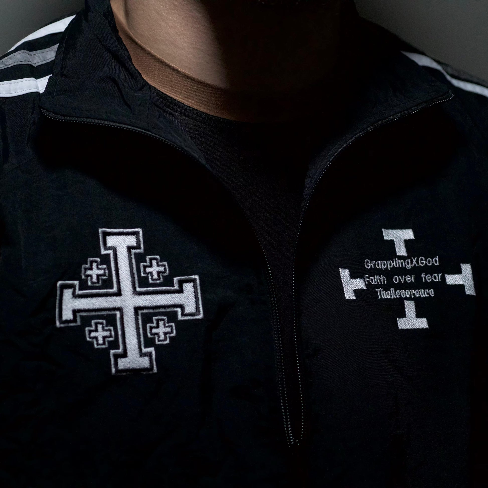 Black jacket with white cross design and text on a dark background