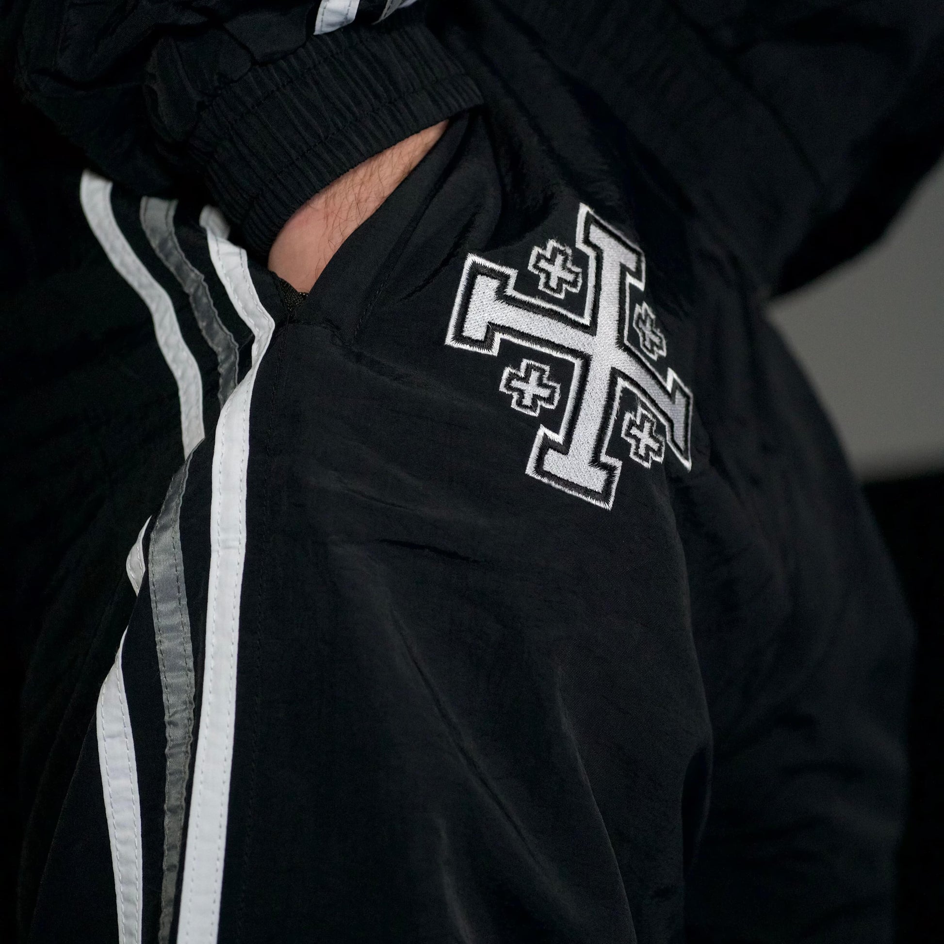 Black tracksuit with white cross design on a dark background
