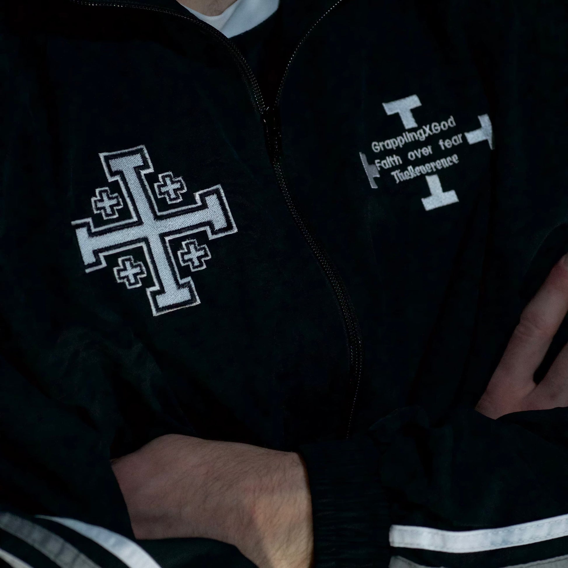Black jacket with white cross design and text on a dark background