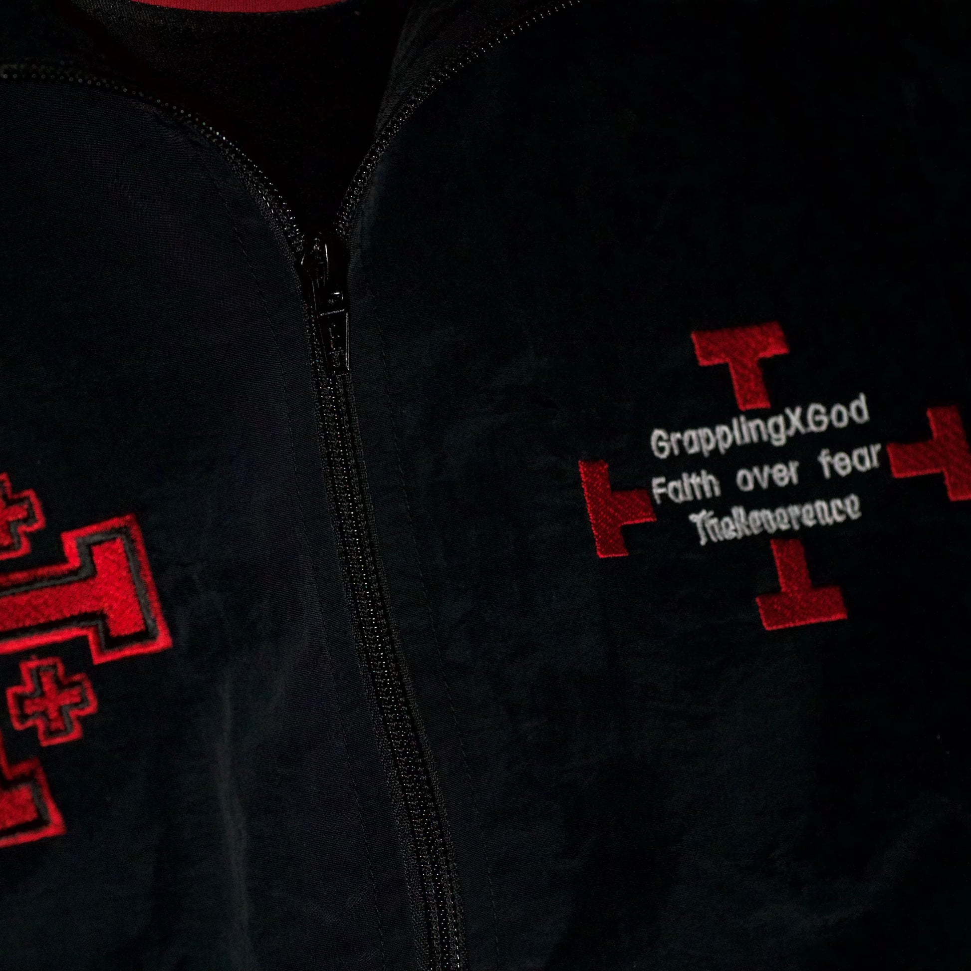 Black jacket with red embroidered designs and text on a dark background