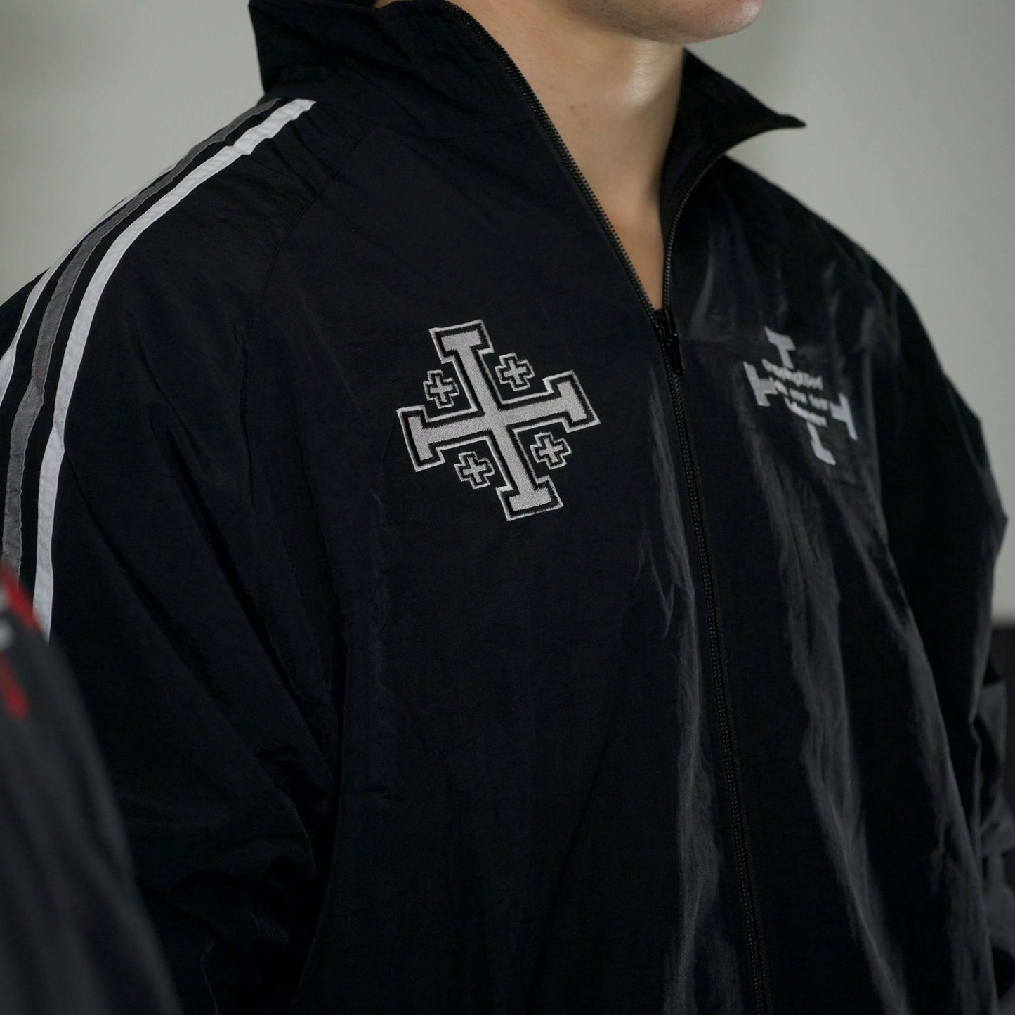 Black jacket with white cross emblem and text on a blurred background