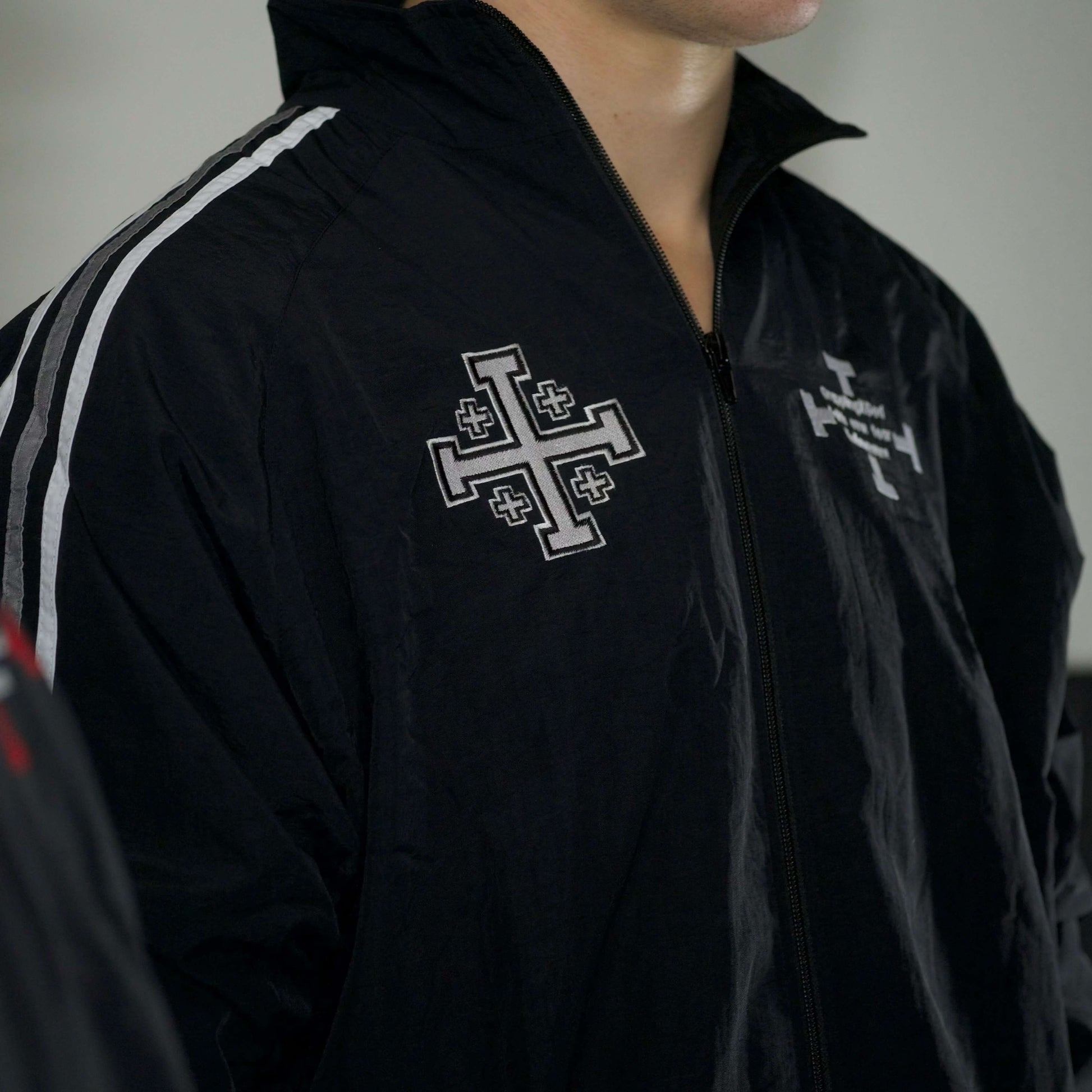 Black jacket with white cross emblem and text on a blurred background