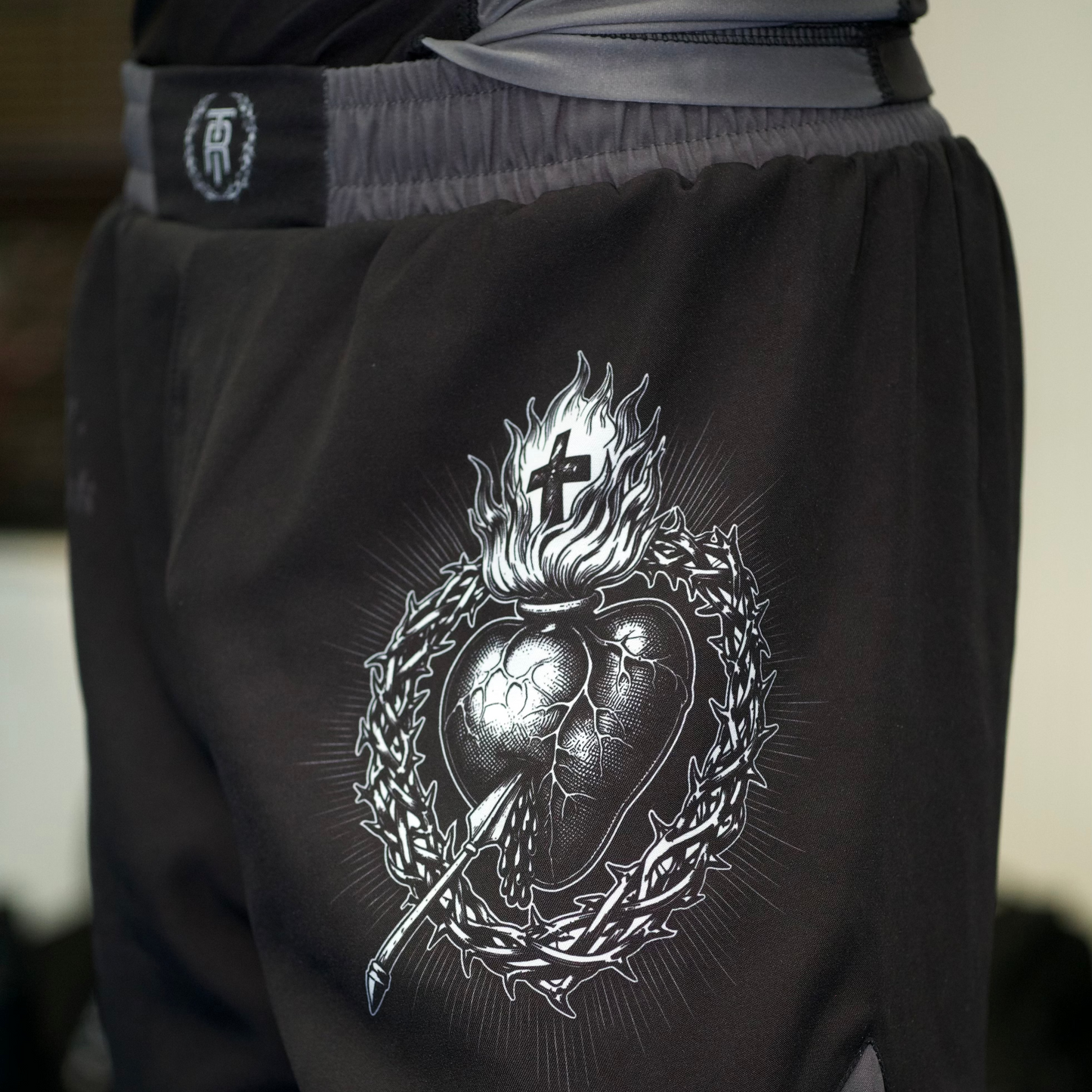 Black shorts with a detailed design on the back, featuring a cross and heart emblem.