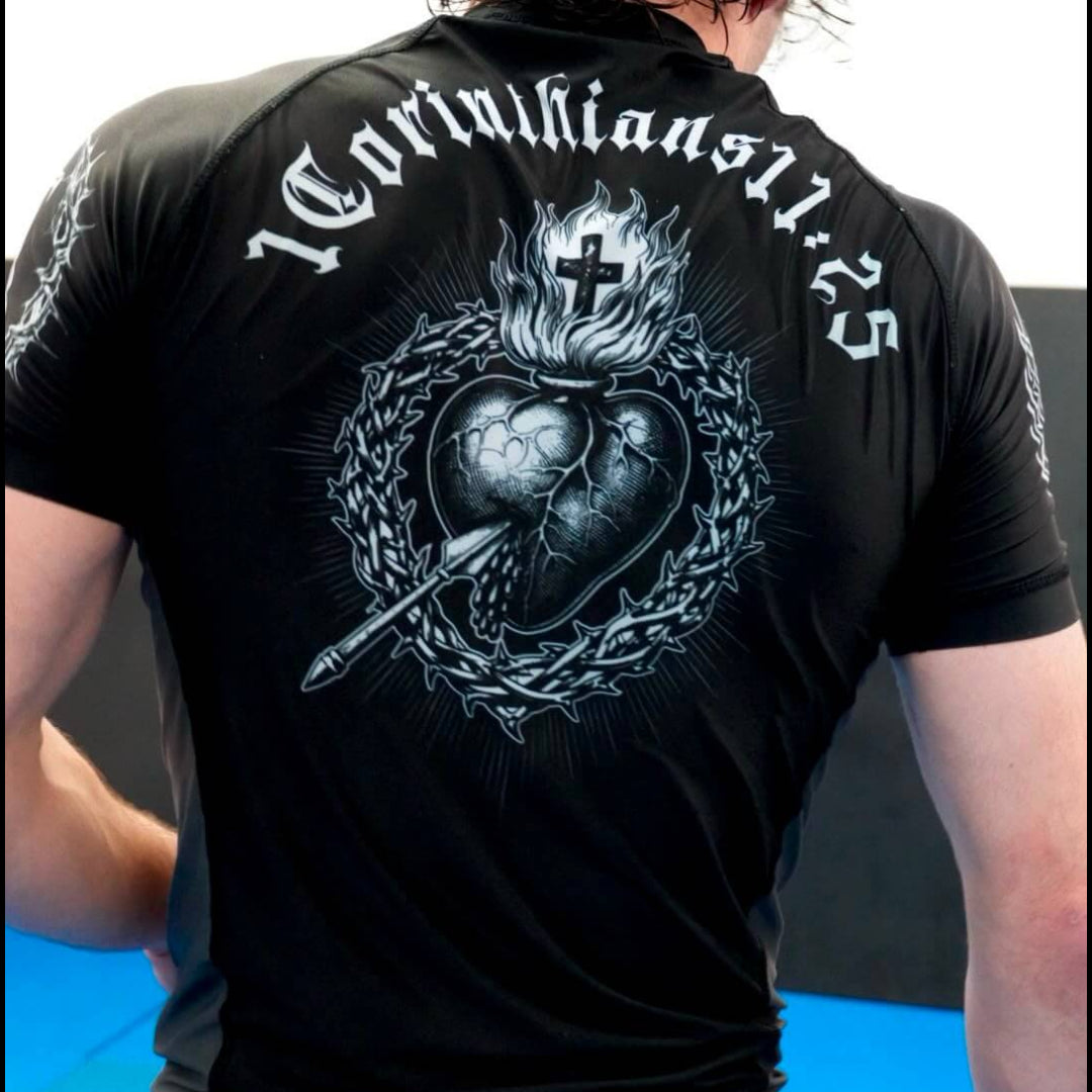 Person wearing a black t-shirt with a design and text on the back, standing against a light blue background.